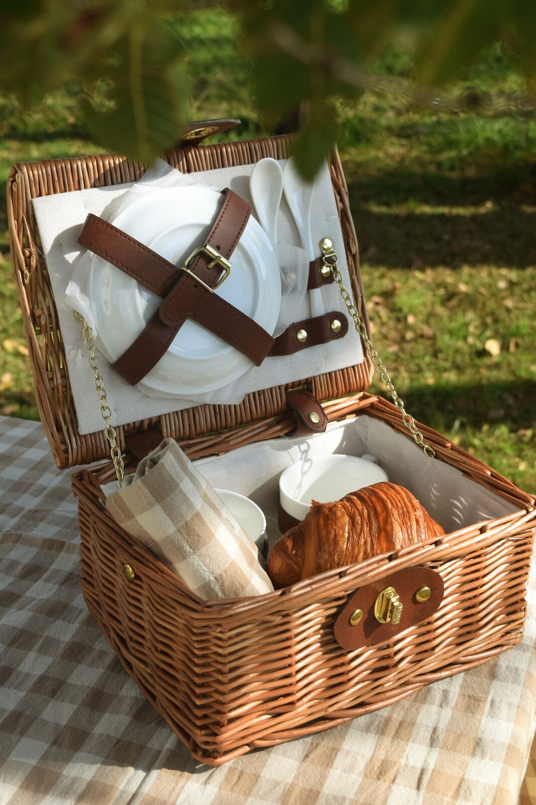 Cesta de picnic con vajilla, taza y croissant