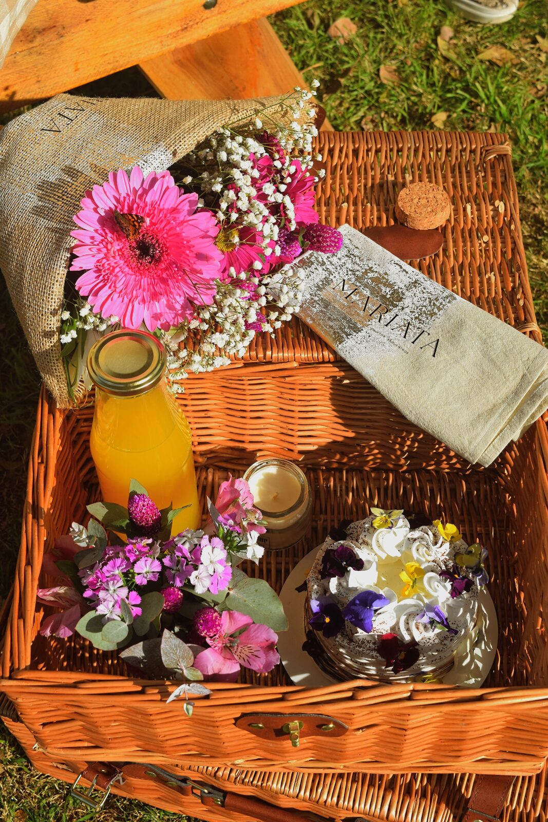 Cesta de picnic con flores frescas y torta